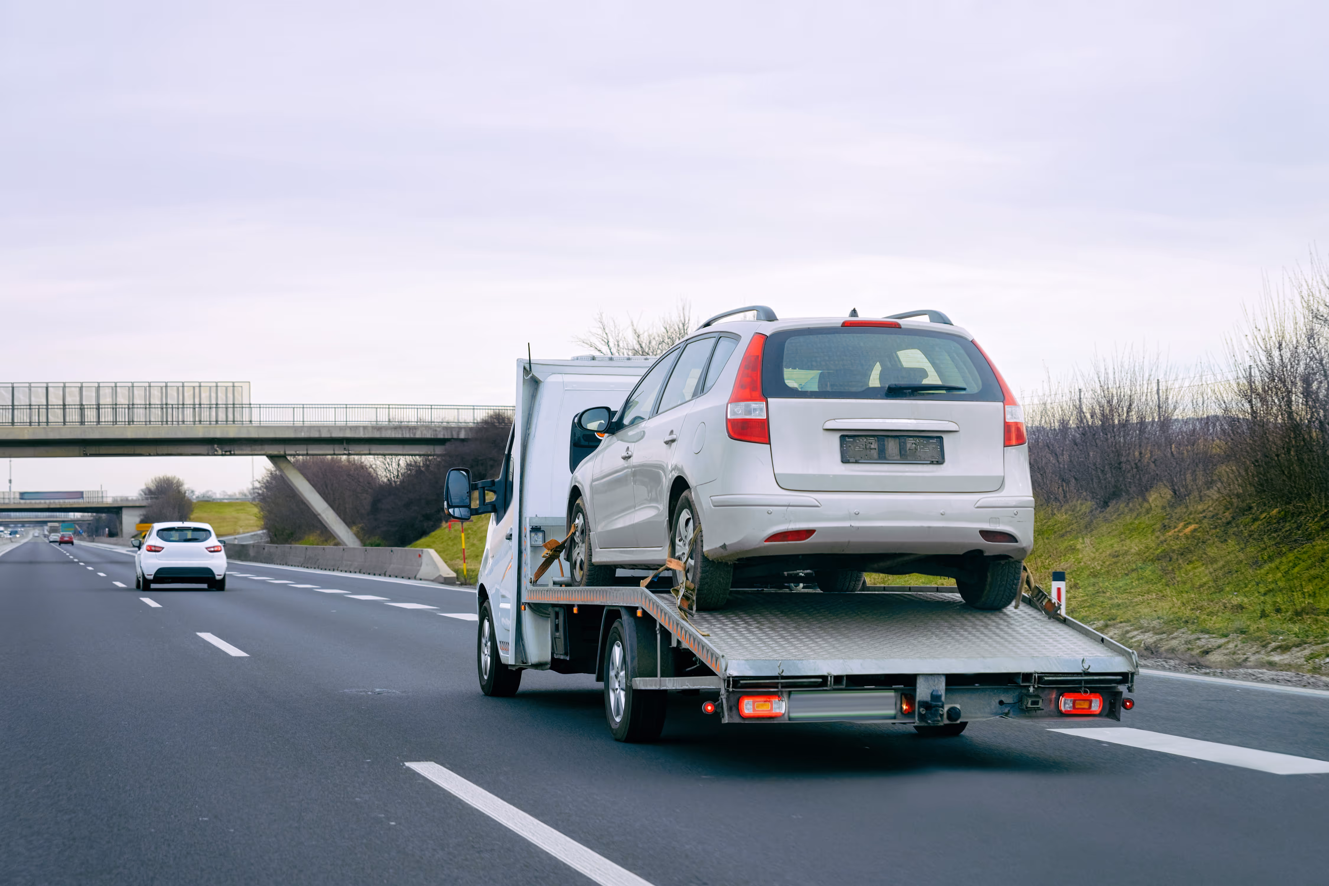 Autotransporter fährt auf der Autobahn, um ein Auto zur Fahrzeugverwertung und Autoentsorgung zu bringen.